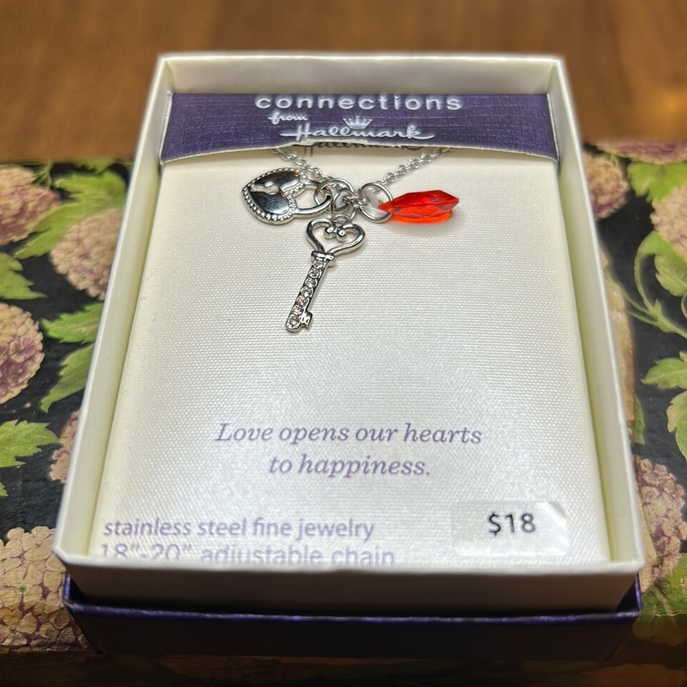 18” stainless steel chain with dangling pendant; key heart and red faceted bead